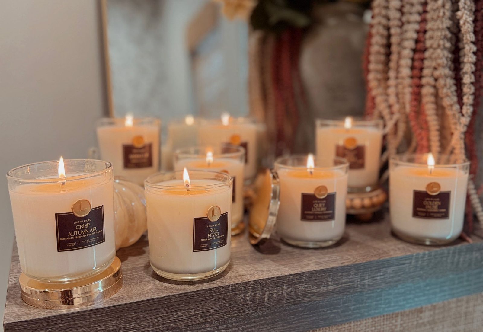 Autumn soy candles lit on a wooden shelf