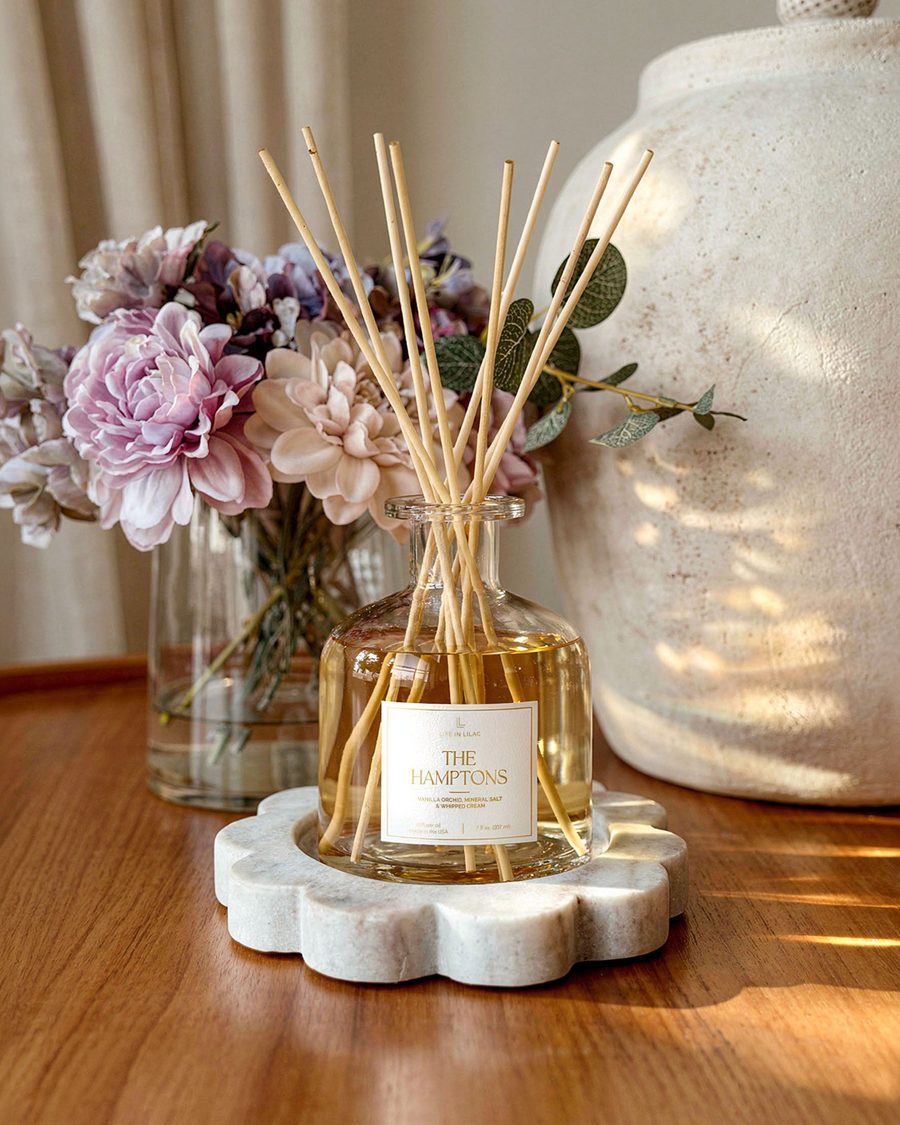The Hamptons reed diffuser beside a vase of flowers